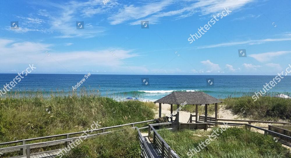 A wooden boardwalk winding through dune grass down to the ocean